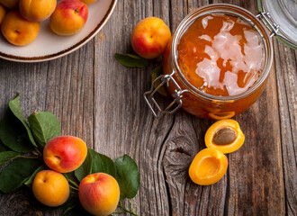 Apricot fruits and apricot jam on the wooden background