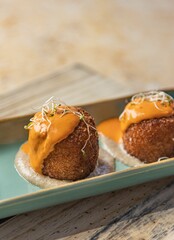 Closeup of small and tasty appetizers in a green plate on the wooden table