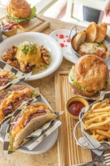 Array of tasty tacos, hamburgers, fries and salads on served the table