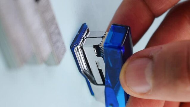 Selective-focus view of a hand picking a blue stapler