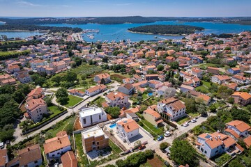 Fototapeta premium Aerial view of residential houses near the sea on a sunny day in Medulin, Croatia