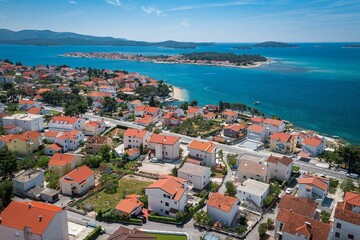 Naklejka na ściany i meble Aerial view of an idyllic coastal scene featuring a tranquil blue ocean and bright white buildings
