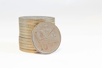 Stack of Ghanaian cedi coins, with 10 pesewas coin on the white background