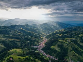 Fototapeta premium Aerial view of Poiana Marului, a picturesque village in Transylvania surrounded by lush green hills