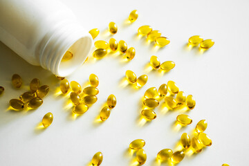 Close up vitamin D3 softgel capsules on a white surface. Yellow softgels, top view, copy space. Nutritional supplements. Health care and immunity support concept.