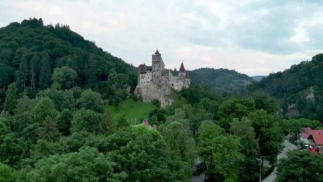 Drone footage around Bran Castle with green landscape of forested hills