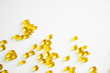 Health care and immunity support concept. Vitamin D3 softgel capsules on a white surface. Yellow softgels, top view, copy space. Nutritional supplements.