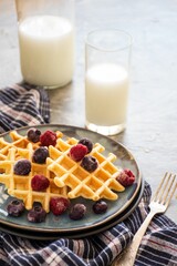 Closeup shot of a plate of waffles served with a glass of cold milk.