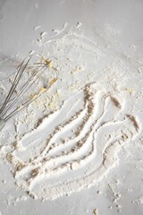 Close-up shot of a whisk on a kitchen countertop with flour.