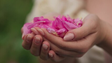 Close-up view of a woman holding rose petals in her palms and smelling - Powered by Adobe