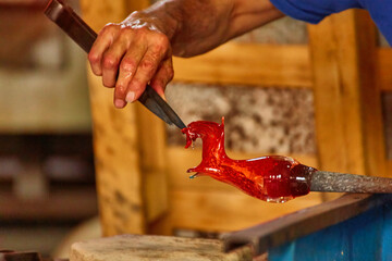 Murano glass blower holds a red hot glass horse sculpture - Powered by Adobe