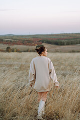 Beautiful model in stylish clothes posing on the autumn field. Fashion concept. Lifestyle, recreation.