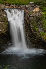 Fototapeta na wymiar Long exposure of tranquil and picturesque waterfall cascading down over a rocky landscape in Norway
