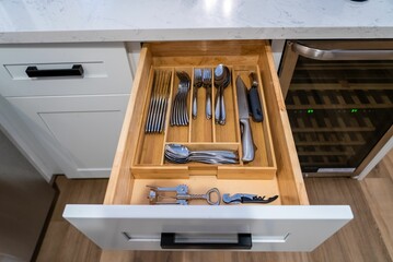 Wooden drawer containing various types of kitchen utensils