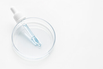 Petri dish. Cosmetic pipette with blue and blue gel, serum, serum on a light background.