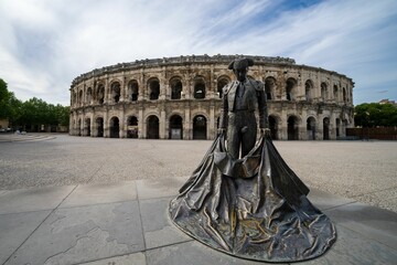 Fototapeta na wymiar Solitary statue standing in the foreground of a large arena: des Arenes, Nimes France