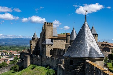Magnificent castle on a lush green hill, overlooking a sprawling cityscape: Cite de Carcassonne