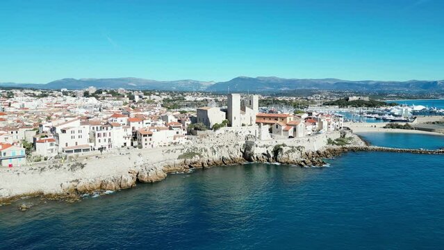 Drone shot of Antibes town with Chateau Grimaldi castle along sea on a sunny day