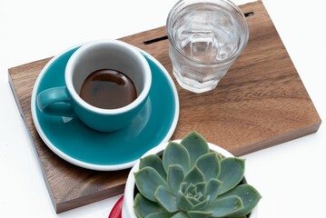 Closeup of a shot of espresso with a glass of water on a tray on the table