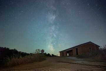 Fototapeta na wymiar Scenic view of a rural barn illuminated by the night sky filled with stars