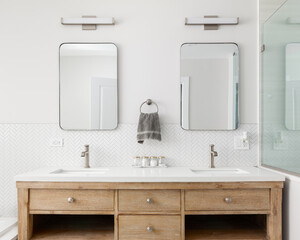 A cozy bathroom detail with a white oak vanity cabinet, white countertop, bronze faucets and lights...