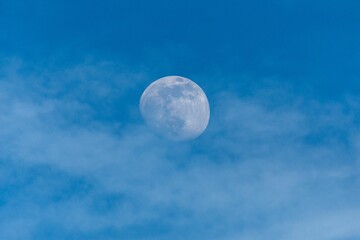 Obraz premium Stunning shot of a full moon in a cloudy blue sky
