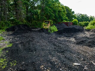 Old and rusted tractor, overgrown with green vines and black mulch on Long Island, New York
