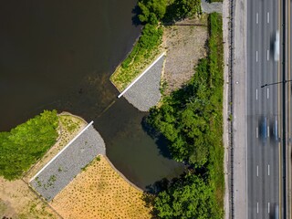 Aerial top view of a road near a water dam on a sunny day