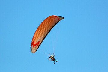 Paramotor pilot flying in a blue sky	