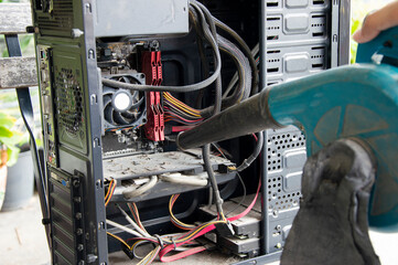 Photograph of a technician blowing dust from a computer