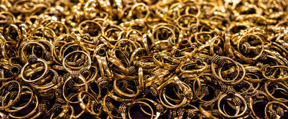 A pile of many gold rings on display at a market.