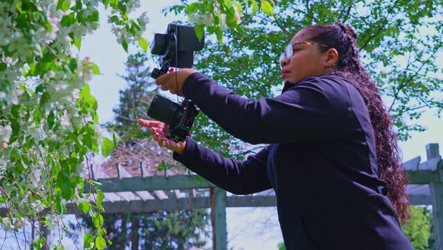 Female traveler videographer or photographer shooting footage of spring colours in the park forest. Travel wanderlust in nature of freelancer nomad, outdoor work concept.