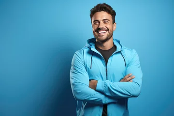 Foto auf Acrylglas Fitness Portrait of smiling young man of athletic build in sports uniform isolated on blue background. Creative banner of fitness center with copy space.