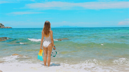 Woman snorkeling in turquoise sea with mask and fins. Tropical beach vacation. Concept of adventurous underwater experience.