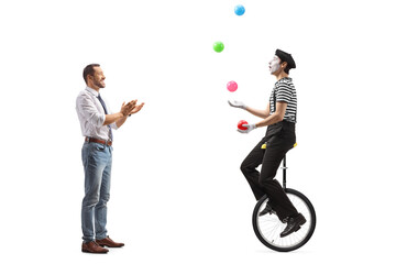 Full length profile shot of a man giving an applause to a mime on a unicycle juggling with balls © Ljupco Smokovski
