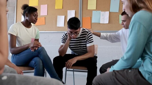Teen high school student receives support from multiracial classmates in group therapy sitting in circle. 4k video.