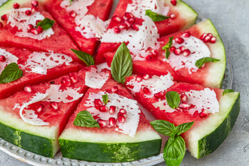 Watermelon pizza with   cheese, pomegranate seeds and basil