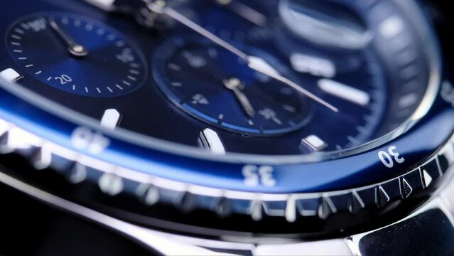 second hand ticking on a blue watch face. Men's chronograph watch in metal with sapphire crystal. closeup view of rotating watch, running second arrow. blue dial