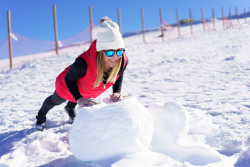 Fototapeta na wymiar Happy woman doing exercise in warm clothes on snow rock