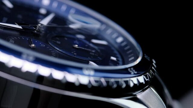 second hand ticking on a blue watch face. Men's chronograph watch in metal with sapphire crystal. closeup view of rotating watch, running second arrow. blue dial