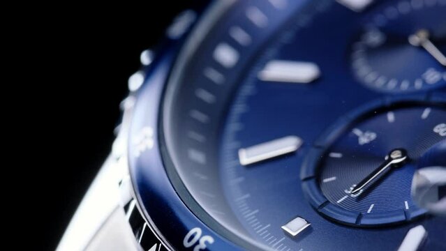 second hand ticking on a blue watch face. Men's chronograph watch in metal with sapphire crystal. closeup view of rotating watch, running second arrow. blue dial