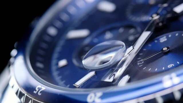 second hand ticking on a blue watch face. Men's chronograph watch in metal with sapphire crystal. closeup view of rotating watch, running second arrow. blue dial