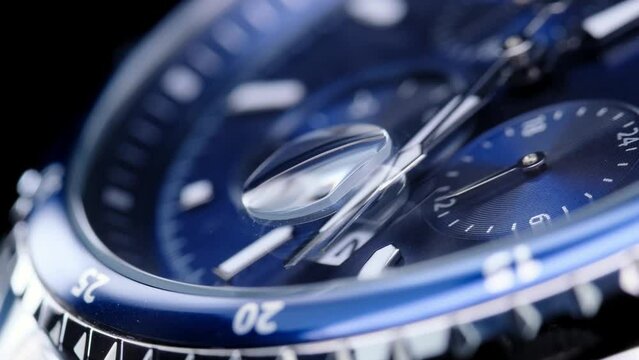 second hand ticking on a blue watch face. Men's chronograph watch in metal with sapphire crystal. closeup view of rotating watch, running second arrow. blue dial