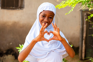 young African Muslim girl creating a heart shape with her hands