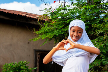 young African Muslim girl making a heart with her hands