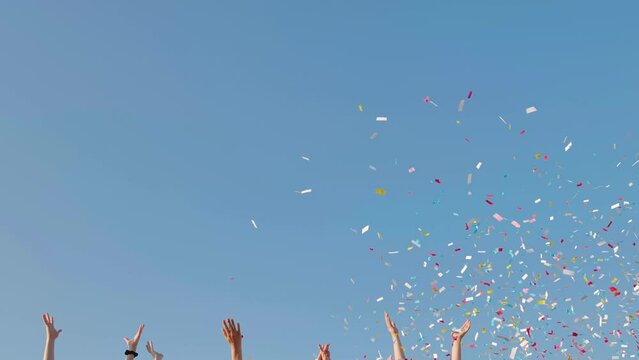 Tossing colorful paper confetti from the hands of young people.