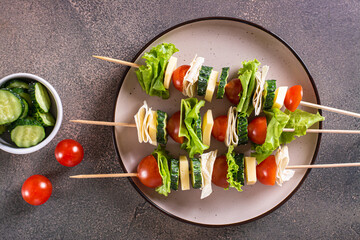 Close up of skewers of tomatoes, cucumber, cheese, pita bread and lettuce on a plate top view
