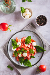 Delicious caprese salad with ripe tomatoes, mozzarella cheese and basil on a plate top and vertical view