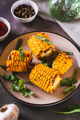 Grilled corn with spices, butter and garlic on a plate on the table vertical view