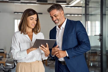 Two diverse partners walking mature Latin business man and European business woman discussing...